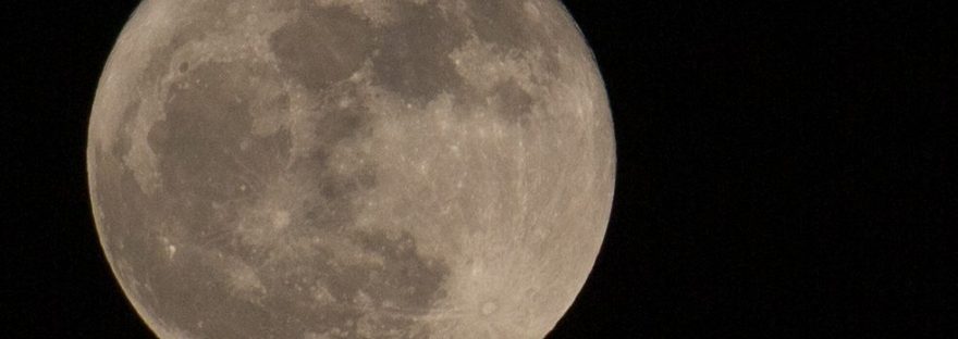 Image of a full moon against a black, starless sky.